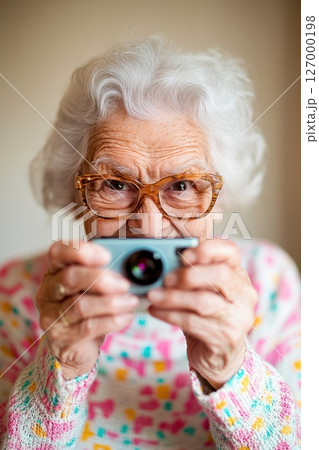 Elderly woman with white hair capturing memories with a camera in a cozy indoor setting during daylight 127000198