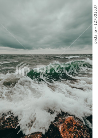 Stormy ocean waves crashing against rocks under cloudy sky landscape 127001637