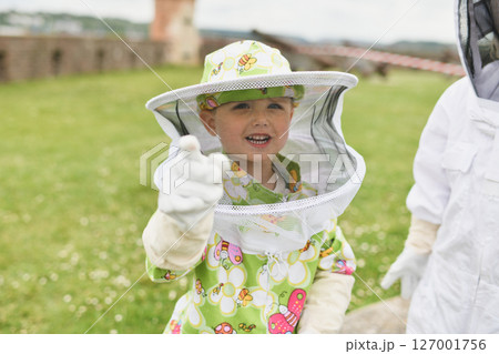 Beekeeper child in apiary in a protective suit 127001756