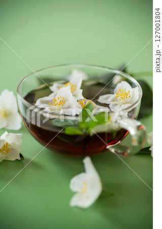 Fragrant jasmine tea in a glass container on a green background Fragrant jasmine tea in a glass container on a green background 127001804
