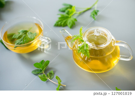 Tea in a glass teapot and cup with currant and mint leaves Tea in a glass teapot and cup with currant and mint leaves 127001819