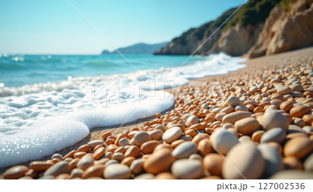 A serene pebble beach with gentle waves. 127002536