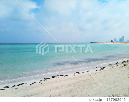 View of Ajman. A serene and picturesque view of a pristine beach in the United Arab Emirates, where the soft golden sands meet the crystal-clear turquoise waters of the Arabian Gulf. View of Ajman. A serene and picturesque view of a pristine beach in the United Arab Emirates, where the soft golden sands meet the crystal-clear turquoise waters of the Arabian Gulf. 127002943