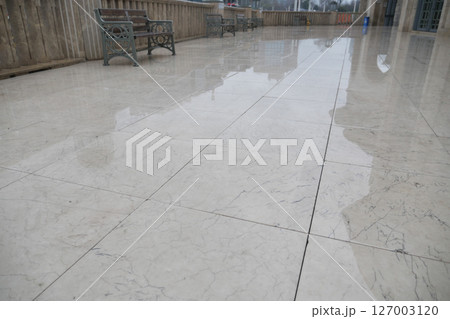 Wet marble floor in a courtyard after rain on a cloudy day 127003120