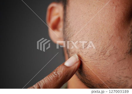 Close-up of a person's hand touching facial hair in natural light 127003189