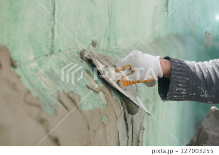A worker smooths plaster on a wall in a renovation project 127003255