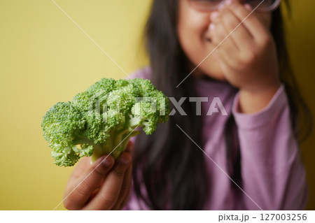 Child holds broccoli while laughing in the kitchen Child holds broccoli while laughing in the kitchen 127003256