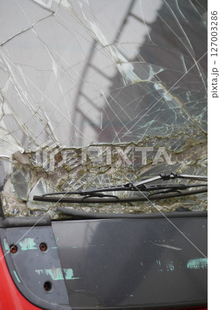 Broken windshield on a red vehicle in an urban setting 127003286