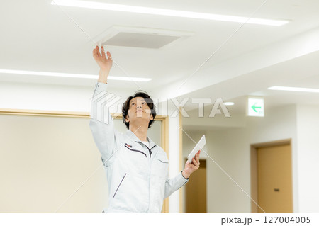 オフィスの換気口を点検するビジネスマン 127004005