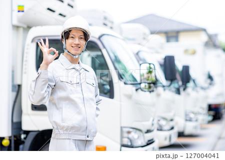 トラックの前で立つ作業服の若い男性 127004041