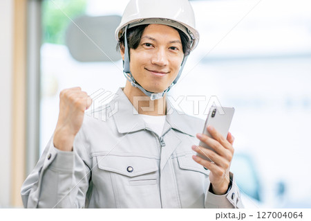 作業服を着たスマホを持つ男性 127004064