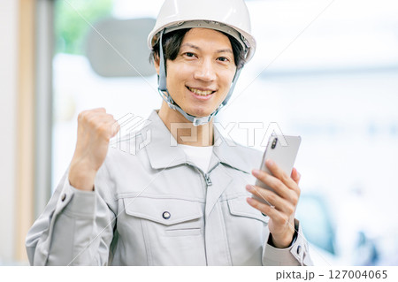 作業服を着たスマホを持つ男性 127004065
