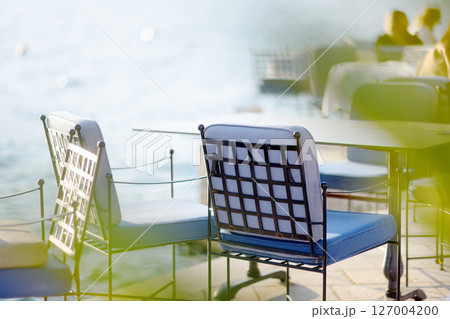 Tables are waiting for visitors or tourists on street in a Mediterranean cafe with national cuisine. The summer veranda of the restaurant near sea 127004200