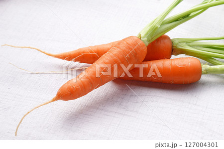 Organic mini carrots with leaves isolated on white wood background. Organic mini carrots with leaves isolated on white wood background. 127004301
