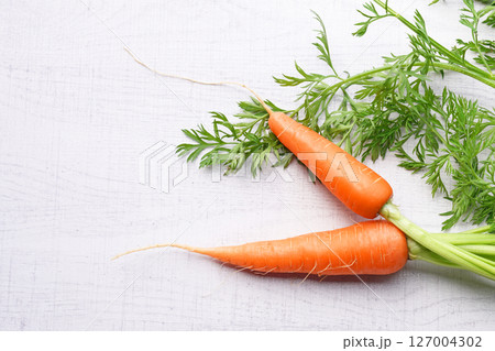Organic mini carrots with leaves isolated on white wood background. Organic mini carrots with leaves isolated on white wood background. 127004302