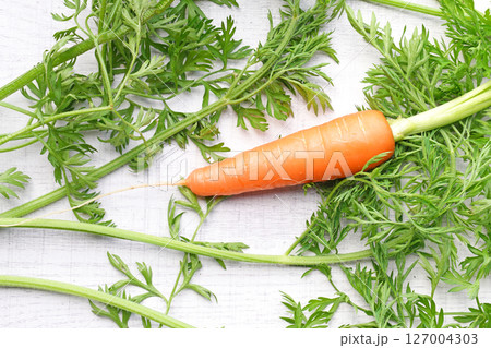 Organic mini carrots with leaves isolated on white wood background. Organic mini carrots with leaves isolated on white wood background. 127004303