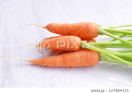 Organic mini carrots with leaves isolated on white wood background. 127004315