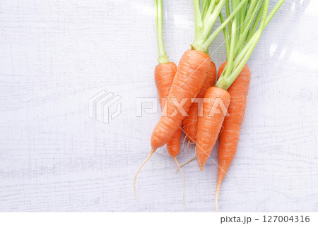 Organic mini carrots with leaves isolated on white wood background. 127004316