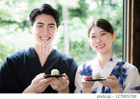 縁側でおまんじゅうや和菓子食べる浴衣の男女 旅館や宿の旅行イメージ カメラ目線 縁側でおまんじゅうや和菓子食べる浴衣の男女 旅館や宿の旅行イメージ カメラ目線 127005788