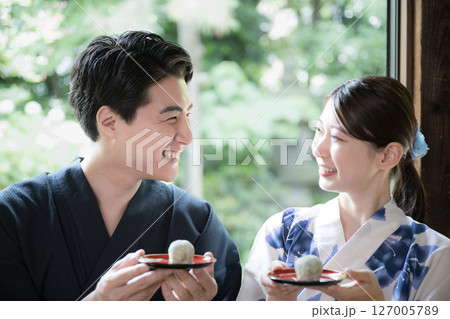 縁側でおまんじゅうや和菓子食べる浴衣の男女　旅館や宿の旅行イメージ 127005789