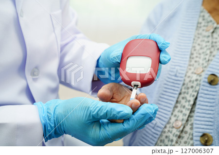 Asian doctor using digital glucose meter for check sample blood sugar level to treatment diabetes. 127006307