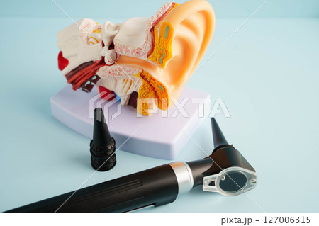 Otoscope with ear model for otolaryngologist or ENT physician doctor examining senior patient ear, hearing loss problem. 127006315