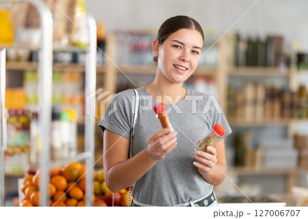 European youth girl choose and buy spices in store 127006707