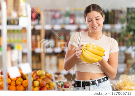 Young woman choosing bananas at grocery store 127006712