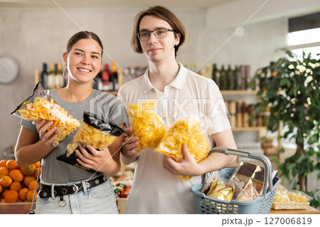 Couple young man and woman choosing chips or snack mix 127006819