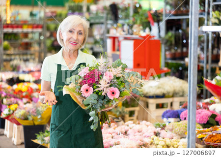 Portrait of happy hostess of flower market with bouquet in her hands Portrait of happy hostess of flower market with bouquet in her hands 127006897