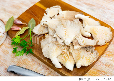 There is bunch of raw oyster mushrooms on chopping board. 127006932