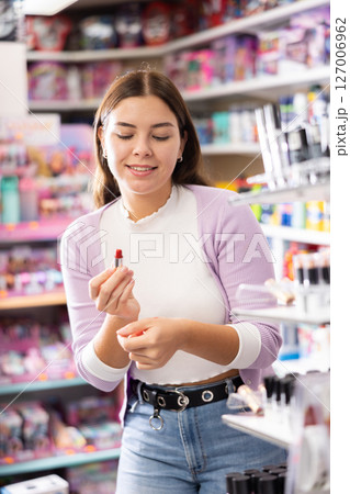 Young female customer searching for reliable lipstick in cosmetics shop 127006962