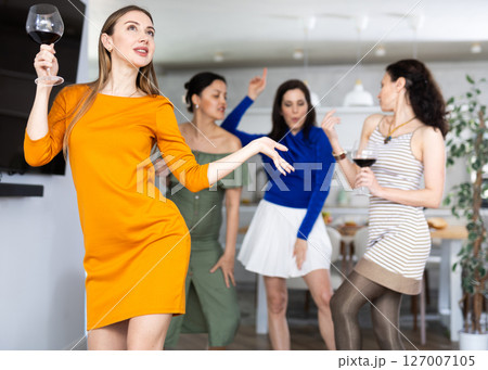 Carefree woman dancing with female friends at home party 127007105