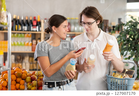 Couple man and woman scanning qr code for sauces Couple man and woman scanning qr code for sauces 127007170
