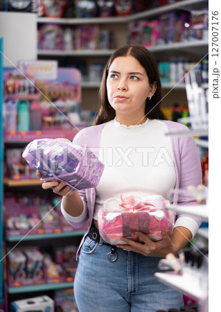 Smiling woman chooses a gift set for someone in cosmetics store 127007176