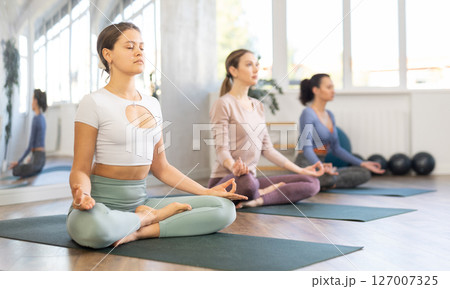 Young girls making yoga meditation in lotus pose in fitness studio 127007325