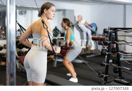 Athletic young woman using exercise machine with ropes at gym Athletic young woman using exercise machine with ropes at gym 127007388