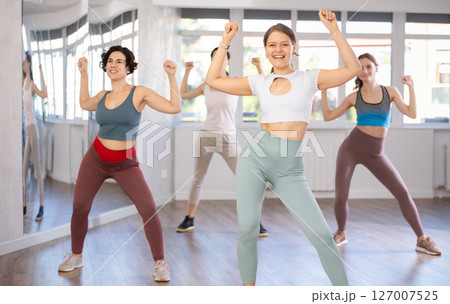Emotional female dancer rehearsing popping techniques during group workout 127007525
