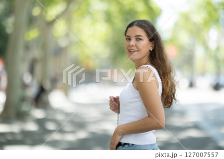 Girl turning with calm relaxed expression on sunny street Girl turning with calm relaxed expression on sunny street 127007557
