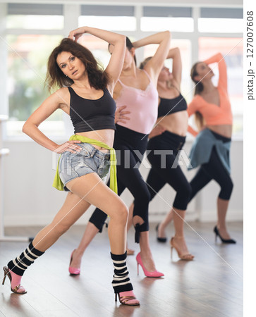 Female instructor performing graceful sass dance movements during group class 127007608