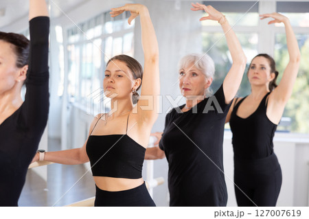 Young girl performing third position at ballet barre Young girl performing third position at ballet barre 127007619