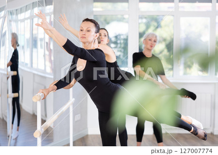 Elderly woman teacher corrects female dancers Elderly woman teacher corrects female dancers 127007774