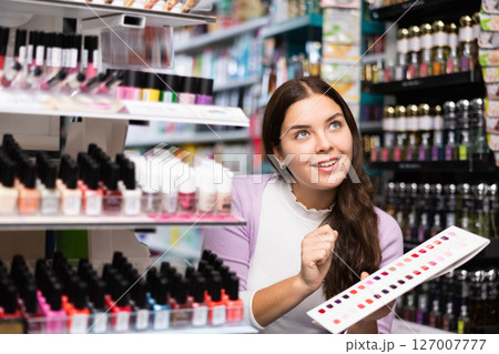 Girl choosing nail polish from color samples in makeup store Girl choosing nail polish from color samples in makeup store 127007777