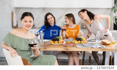 Smiling Asian woman enjoying home get-together with female friends Smiling Asian woman enjoying home get-together with female friends 127007824