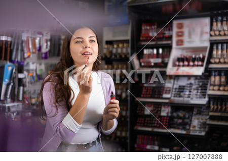 Girl is searching for reliable lipstick in cosmetics shop Girl is searching for reliable lipstick in cosmetics shop 127007888