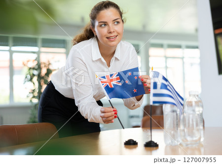 Young female secretary preparing room for international negotiations between greece and new zealand Young female secretary preparing room for international negotiations between greece and new zealand 127007955