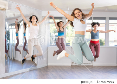 Cheerful girl captured jumping during lively dance fitness routine 127007993