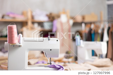 Sewing machine with thread spools in tailoring workshop 127007996