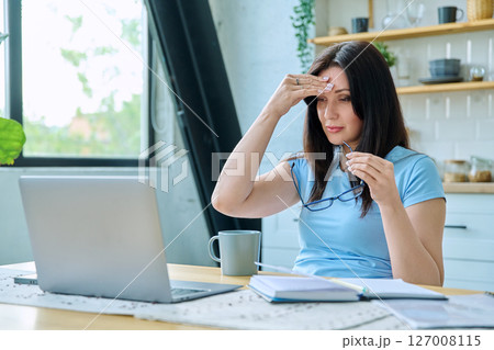Sad stressed woman sitting at home at table with computer Sad stressed woman sitting at home at table with computer 127008115