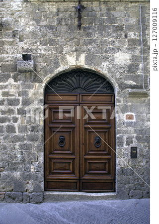 Old wooden door on a house wall. Conceptual image. Wooden Door on an Old House Wall. Architectural Details Worn and Weathered by Time.  127009116